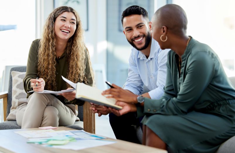three professionals smiling and talking in an office setting