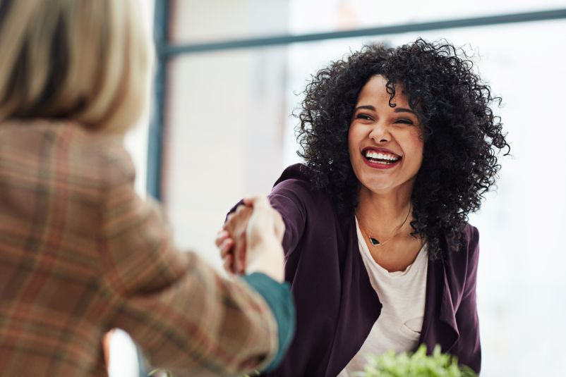 smiling professional woman shaking hands with a colleague