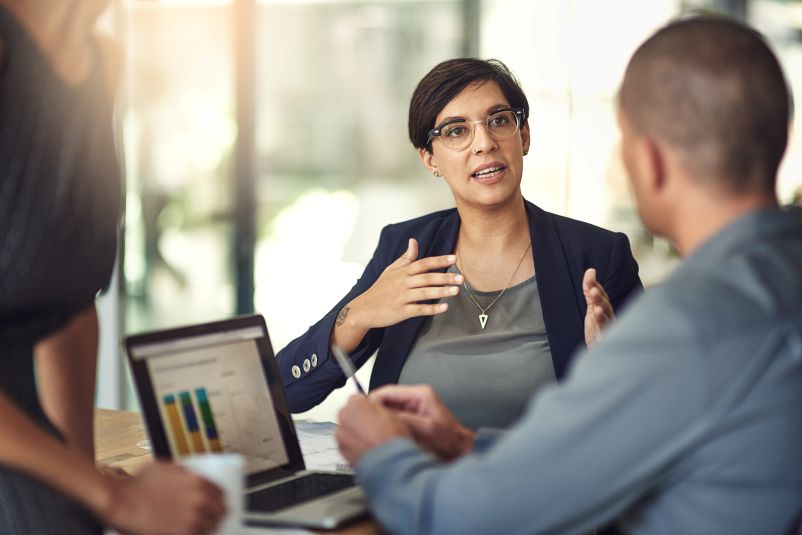 professional woman with dark hair speaking to clients